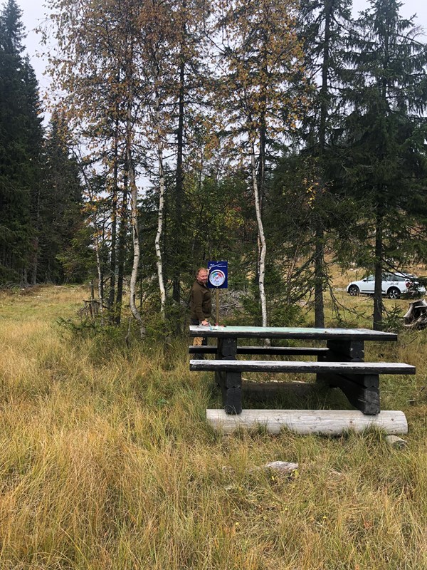 Skiltmaker Sverre Sjøblom monterer nytt skilt med termometer ved det fine kartbordet på Trantjern. Foto: Tore Heldrup Rasmussen